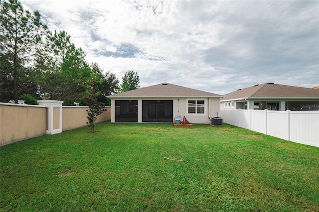 back of house with a sunroom, central air condition unit, and a lawn