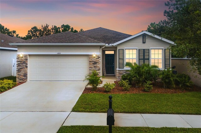 ranch-style house with a garage and a yard