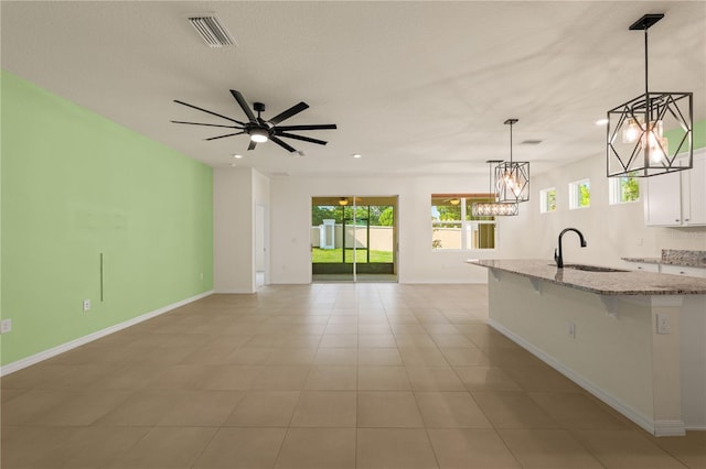 11892 Frost Aster Dr, Riverview, FL 33579 - kitchen featuring a sink, a kitchen bar, white cabinetry, light stone countertops, and a center island with sink