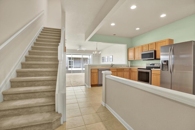 kitchen featuring sink, light tile patterned floors, decorative light fixtures, kitchen peninsula, and stainless steel appliances