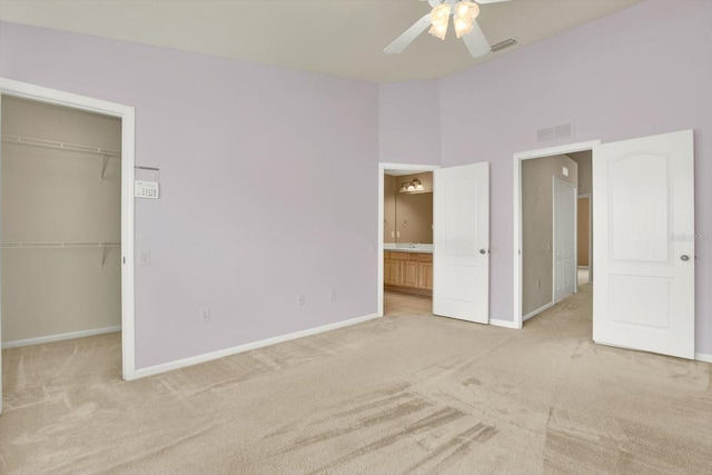 unfurnished bedroom with light carpet, a high ceiling, a closet, and ceiling fan