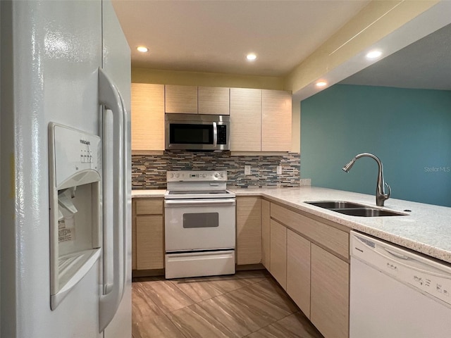 kitchen with white appliances, light brown cabinetry, tasteful backsplash, and sink