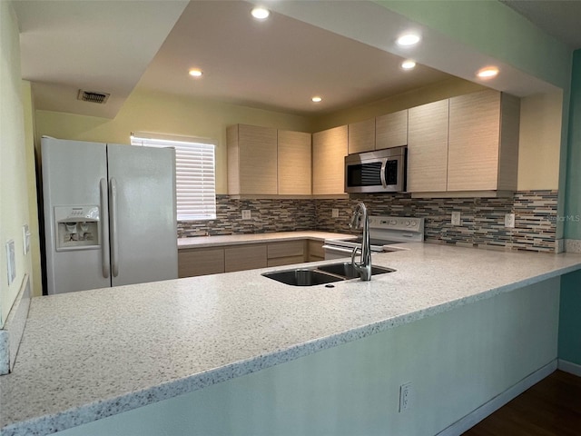 kitchen with kitchen peninsula, dark hardwood / wood-style flooring, stainless steel appliances, and light stone counters