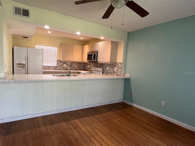 kitchen featuring sink, a textured ceiling, backsplash, appliances with stainless steel finishes, and dark hardwood / wood-style flooring