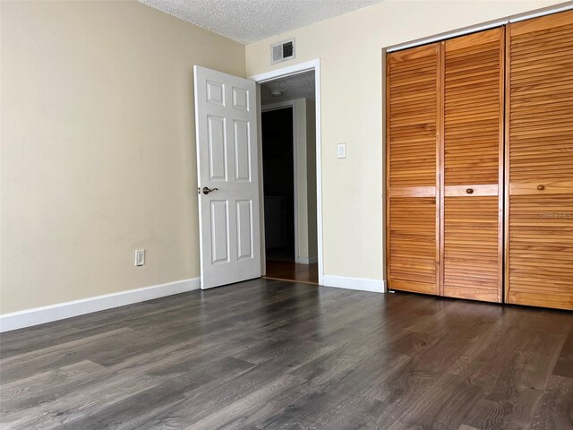 unfurnished bedroom with dark hardwood / wood-style flooring, a closet, and a textured ceiling