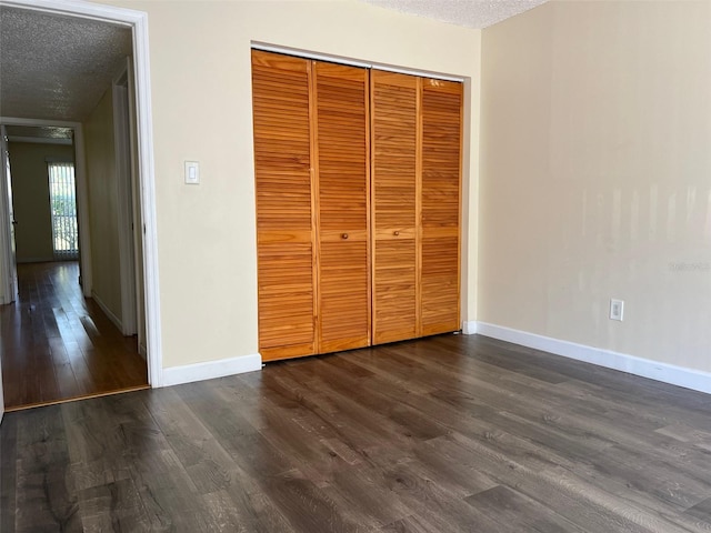 unfurnished bedroom featuring a textured ceiling, a closet, and dark hardwood / wood-style floors