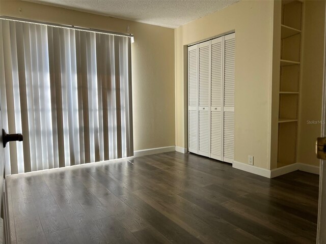 unfurnished bedroom featuring a textured ceiling, a closet, and dark hardwood / wood-style floors