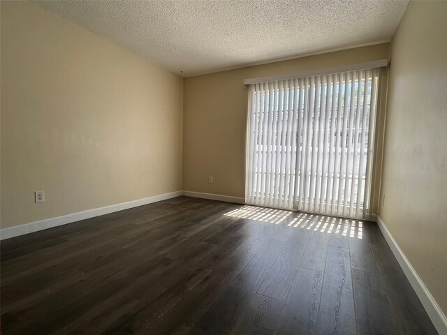 empty room with a textured ceiling and dark wood-type flooring