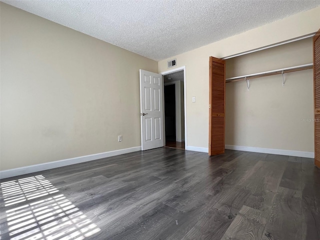 unfurnished bedroom featuring a closet, dark hardwood / wood-style floors, and a textured ceiling