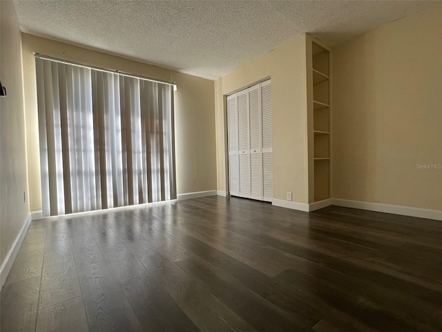 unfurnished room featuring a textured ceiling, dark hardwood / wood-style floors, and built in features