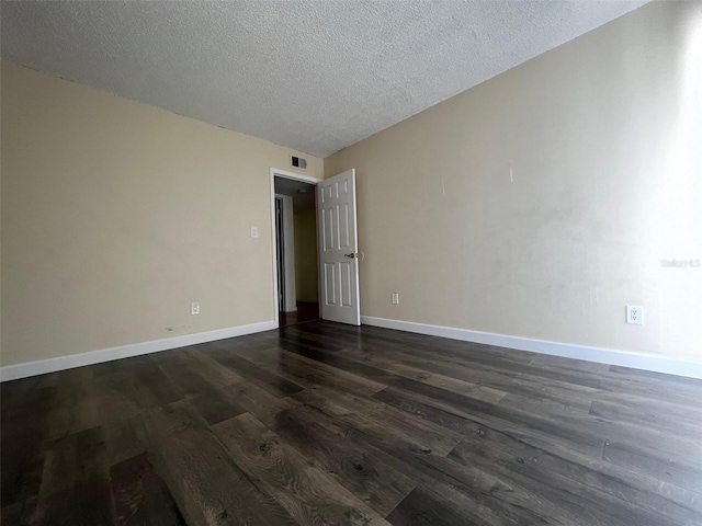 empty room featuring a textured ceiling and dark hardwood / wood-style floors