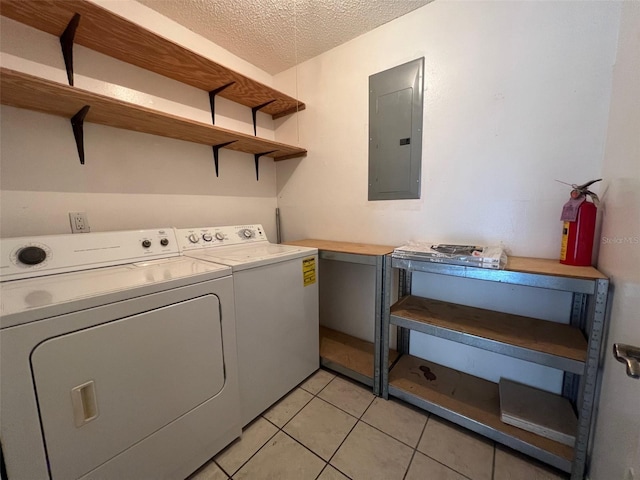 washroom with a textured ceiling, washer and clothes dryer, electric panel, and light tile patterned floors