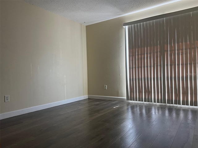 spare room featuring a textured ceiling and dark hardwood / wood-style flooring