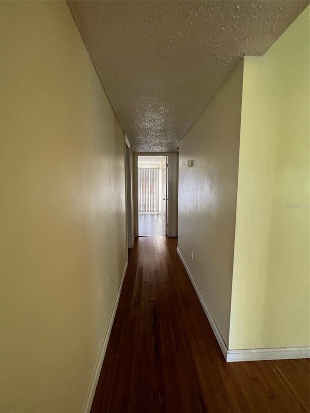 hallway with a textured ceiling and dark wood-type flooring