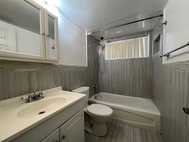 full bathroom with tile walls, tiled shower / bath, vanity, and toilet