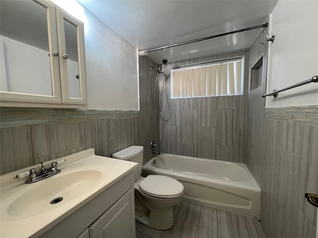 full bathroom featuring vanity, tile walls, tiled shower / bath combo, and toilet