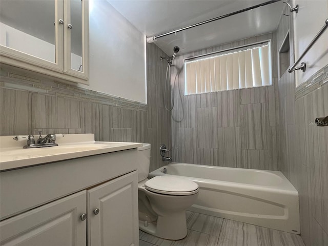 full bathroom with tile walls, tiled shower / bath, vanity, and toilet