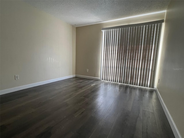 spare room featuring a textured ceiling and dark wood-type flooring