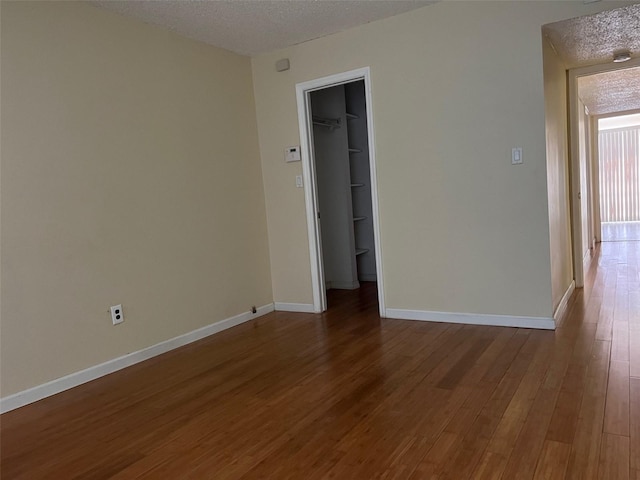 unfurnished room with wood-type flooring and a textured ceiling