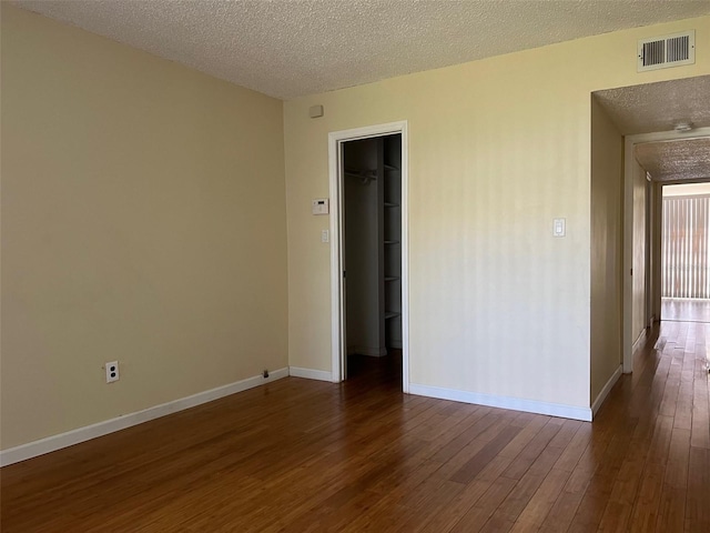 spare room with a textured ceiling and dark wood-type flooring