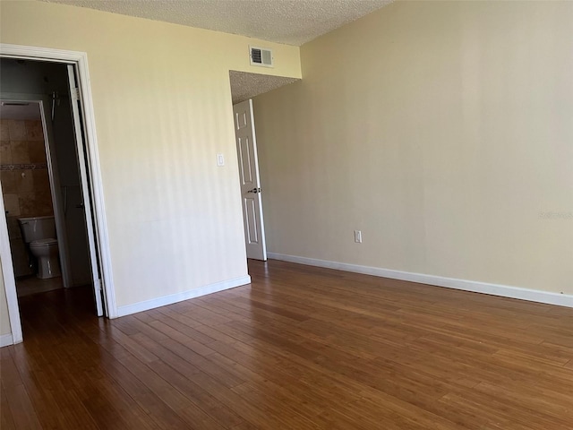 spare room featuring a textured ceiling and dark hardwood / wood-style floors