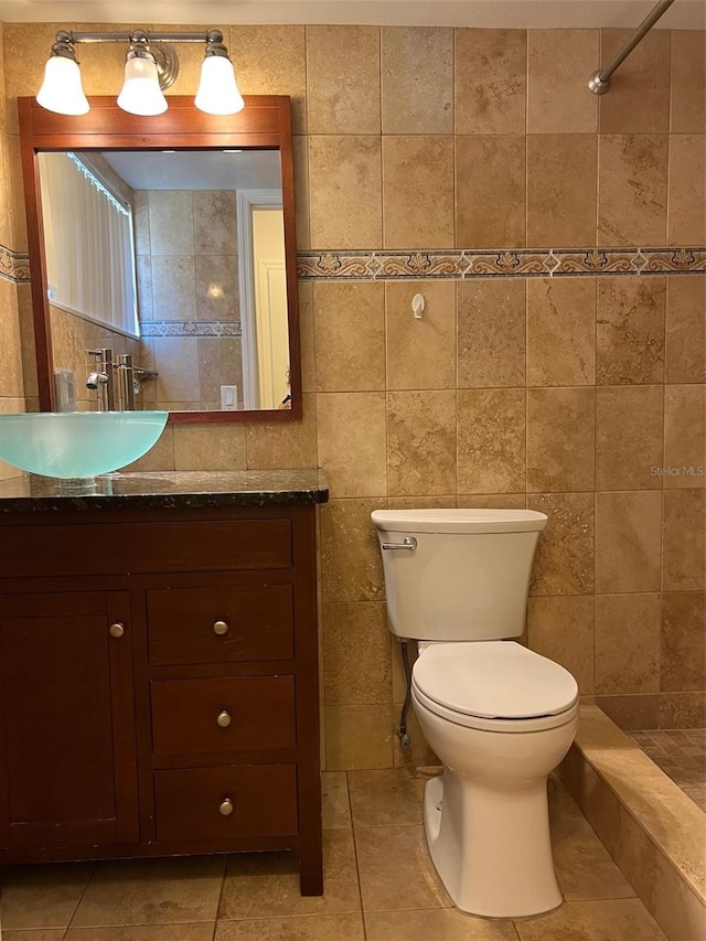 bathroom featuring vanity, tile walls, and toilet