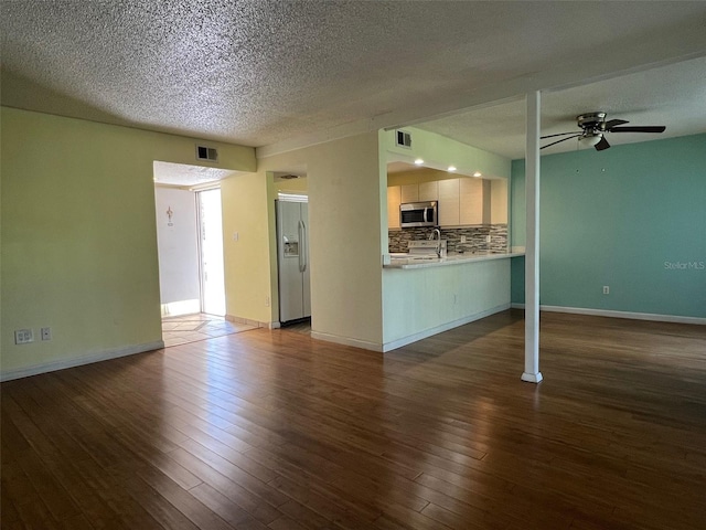 unfurnished living room with a textured ceiling, dark hardwood / wood-style floors, ceiling fan, and sink