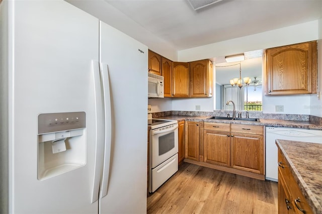 kitchen featuring light hardwood / wood-style flooring, sink, pendant lighting, an inviting chandelier, and white appliances