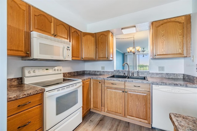 kitchen featuring light hardwood / wood-style flooring, hanging light fixtures, sink, an inviting chandelier, and white appliances