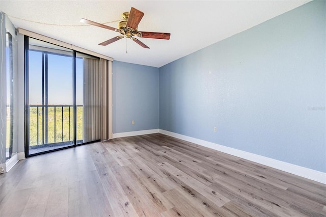 spare room with floor to ceiling windows, light hardwood / wood-style flooring, and ceiling fan