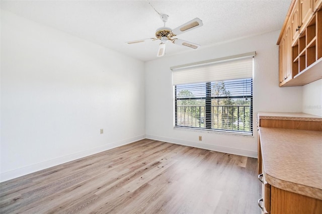 unfurnished dining area featuring ceiling fan, a textured ceiling, and light wood-type flooring