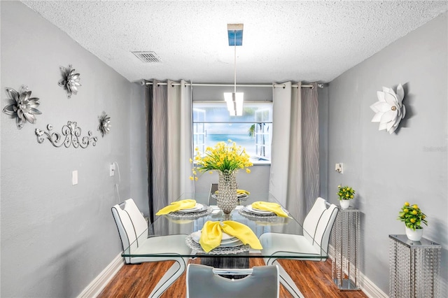 dining space with a textured ceiling and dark wood-type flooring