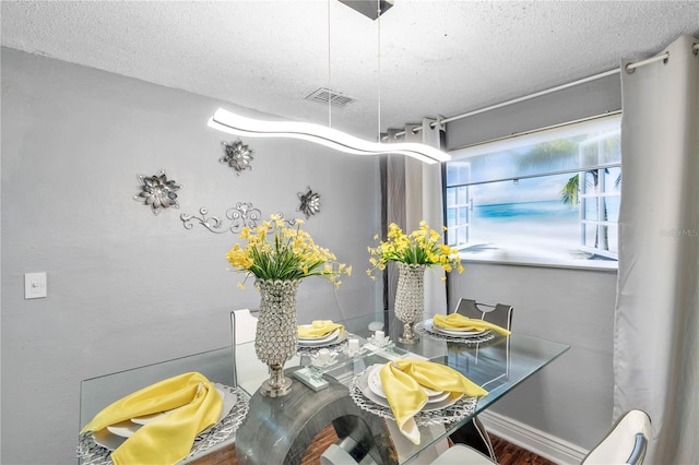 dining area featuring a textured ceiling and hardwood / wood-style flooring