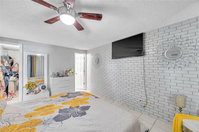 tiled bedroom with brick wall, a textured ceiling, and ceiling fan