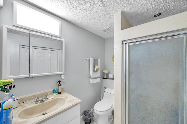 bathroom featuring tile patterned flooring, a textured ceiling, a shower with door, vanity, and toilet