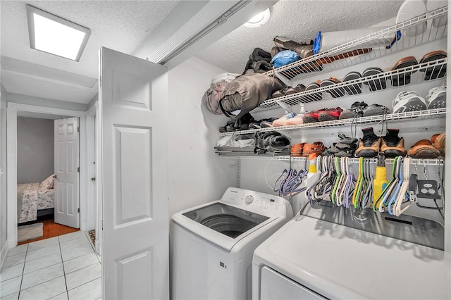 washroom with a textured ceiling, separate washer and dryer, and light tile patterned flooring