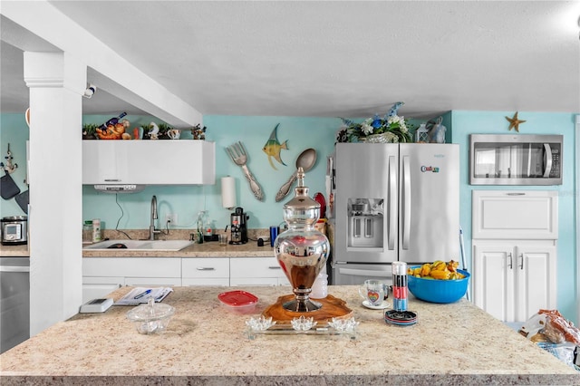 kitchen featuring light stone countertops, sink, stainless steel appliances, and white cabinets