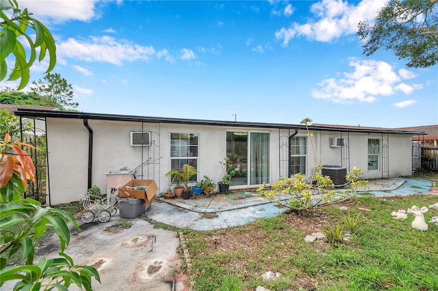 rear view of property with a patio, a wall unit AC, and central AC unit