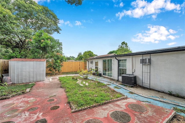 view of yard featuring cooling unit, a storage shed, and a patio area