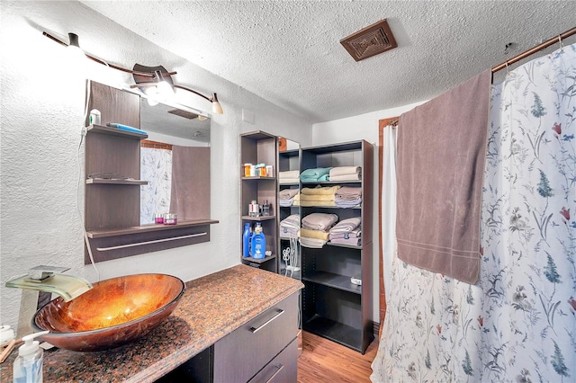 bathroom with wood-type flooring, vanity, and a textured ceiling