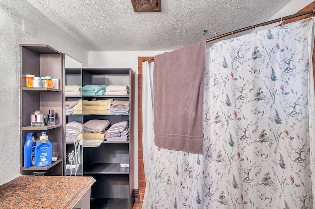 interior space with vanity, a textured ceiling, and curtained shower