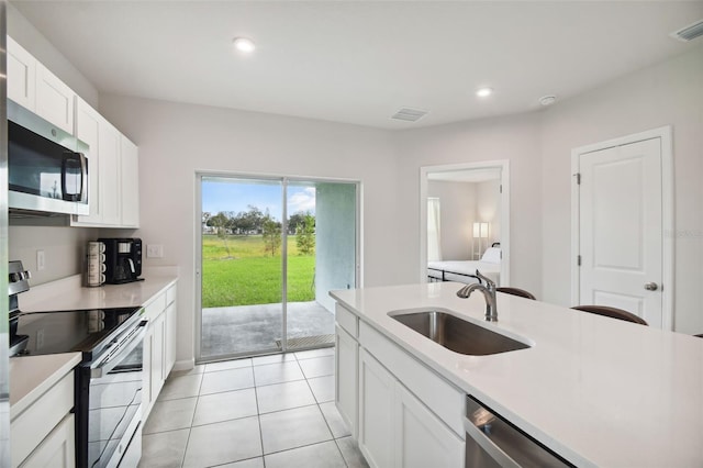 kitchen with white cabinets, sink, light tile patterned flooring, and stainless steel appliances