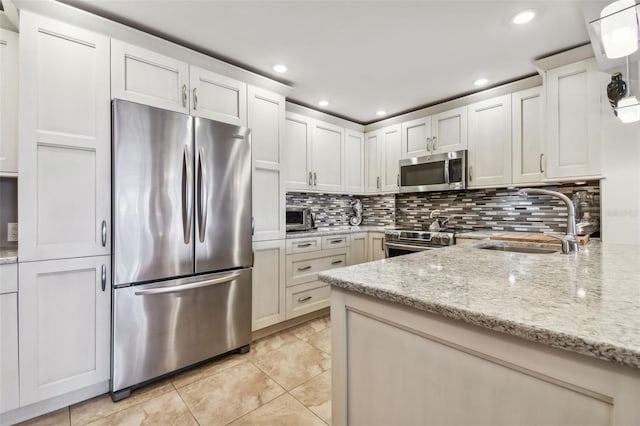 kitchen featuring sink, white cabinets, light stone counters, and appliances with stainless steel finishes