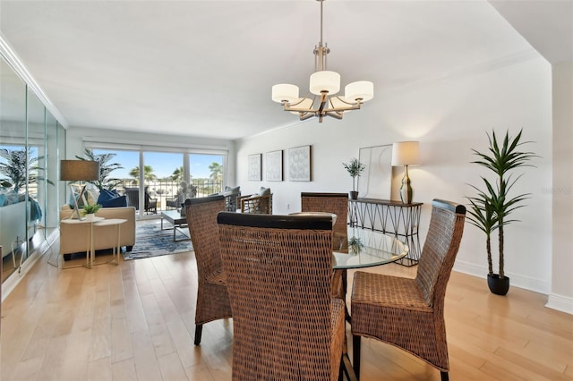 dining area featuring an inviting chandelier, ornamental molding, and light hardwood / wood-style flooring