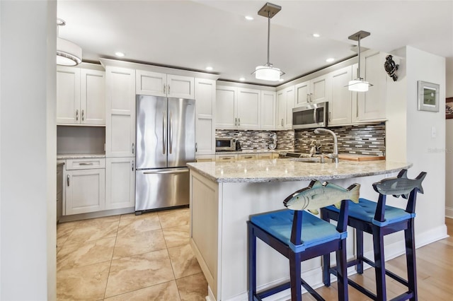 kitchen featuring stainless steel appliances, sink, decorative light fixtures, white cabinets, and kitchen peninsula