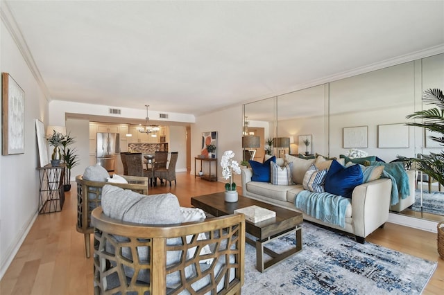 living room with a chandelier, light hardwood / wood-style floors, and crown molding