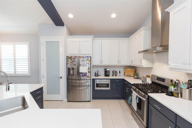 kitchen featuring stainless steel appliances, light tile patterned floors, wall chimney exhaust hood, white cabinets, and sink