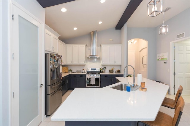 kitchen with stainless steel appliances, wall chimney range hood, an island with sink, and sink