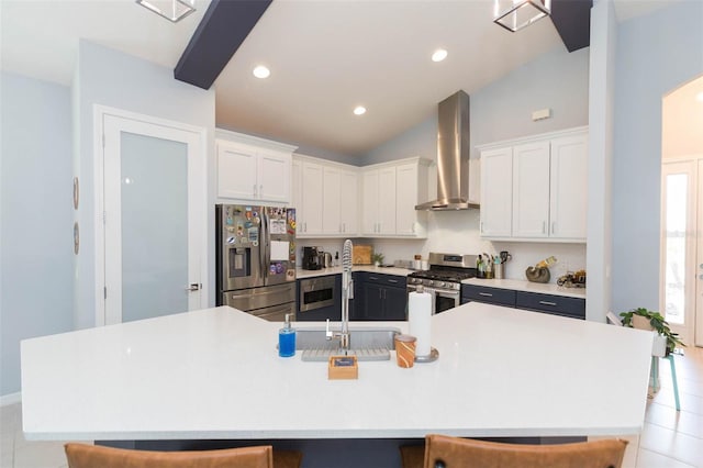 kitchen featuring appliances with stainless steel finishes, white cabinetry, a kitchen bar, and wall chimney exhaust hood