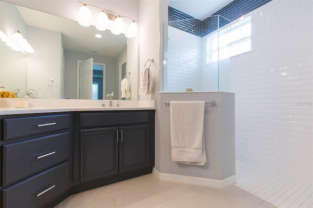 bathroom with a tile shower, vanity, and tile patterned flooring